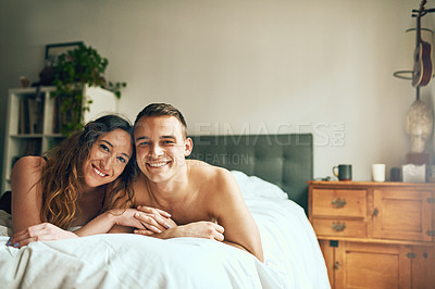 Buy stock photo Portrait of an affectionate young couple spending a romantic morning in bed at home