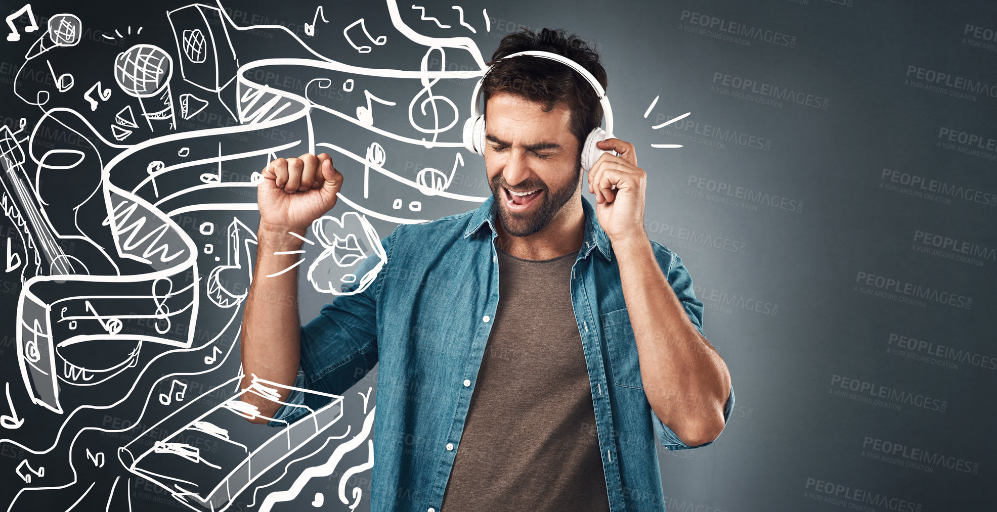 Buy stock photo Studio shot of a handsome young man listening to music while standing beside illustrations against a grey background