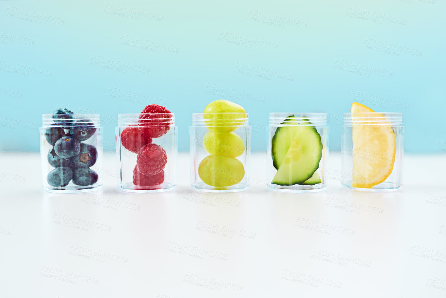 Buy stock photo Studio shot of a conceptual image of natural medication lined up on a table against a blue background