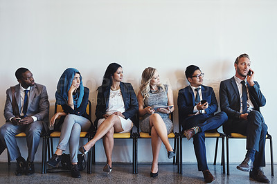 Buy stock photo Shot of a group of confident businesspeople waiting in line for their interviews while a man talks loudly on his cellphone inside of a office during the day