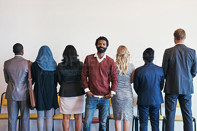Buy stock photo Portrait of a cheerful young businessman standing in line while waiting for an interview and the rest of the candidates have their backs facing the camera