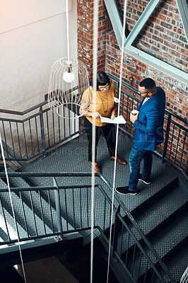 Buy stock photo Shot of two designers having a discussion on a staircase in an offic