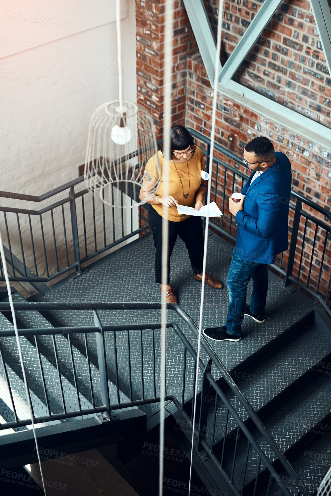 Buy stock photo Shot of two designers having a discussion on a staircase in an offic