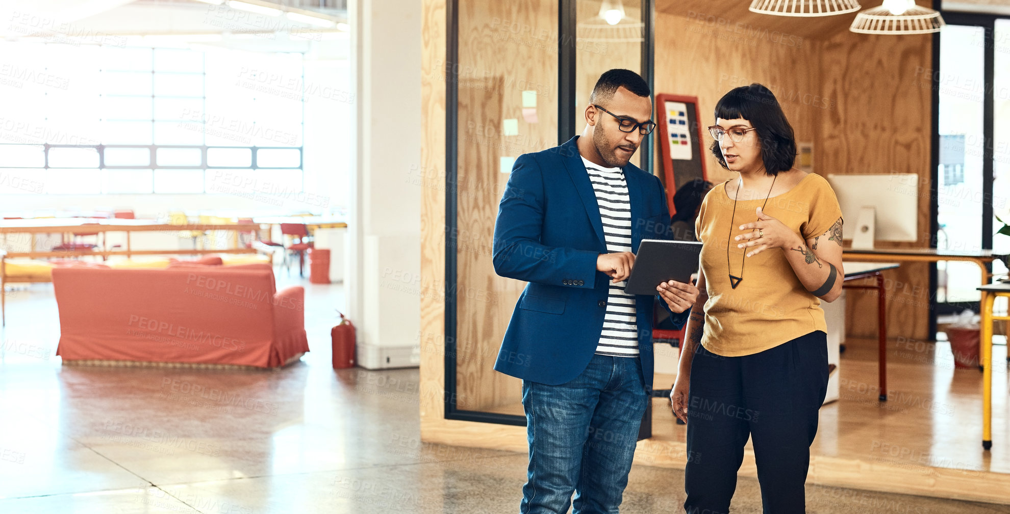 Buy stock photo Shot of two designers working on a digital tablet together in an office