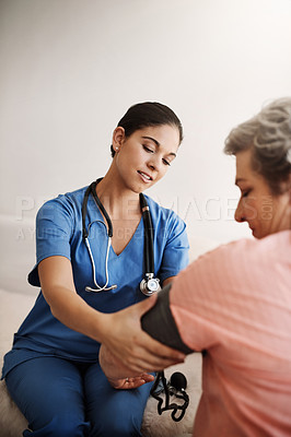 Buy stock photo Cropped shot of an attractive young female nurse checking a senior patient's blood pressure