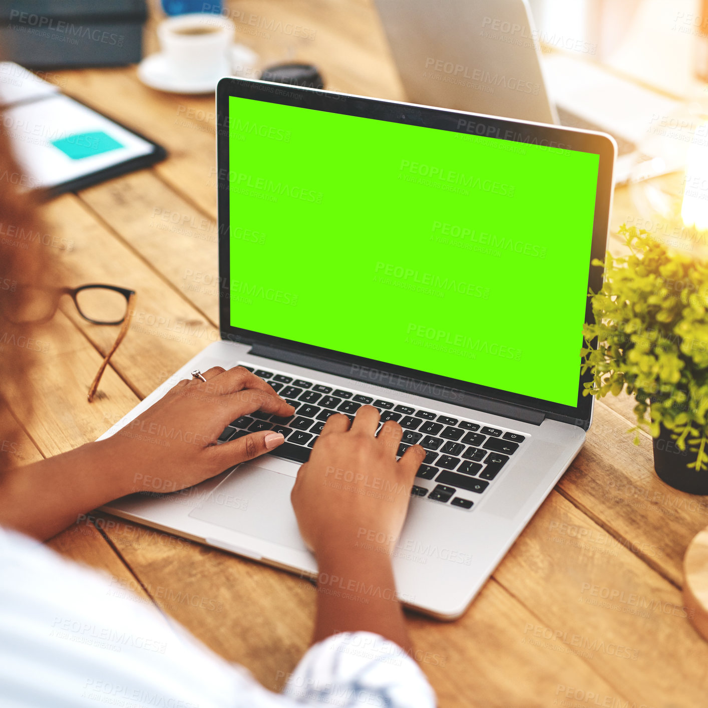 Buy stock photo Cropped shot of an unrecognizable young woman using her laptop on a wooden table