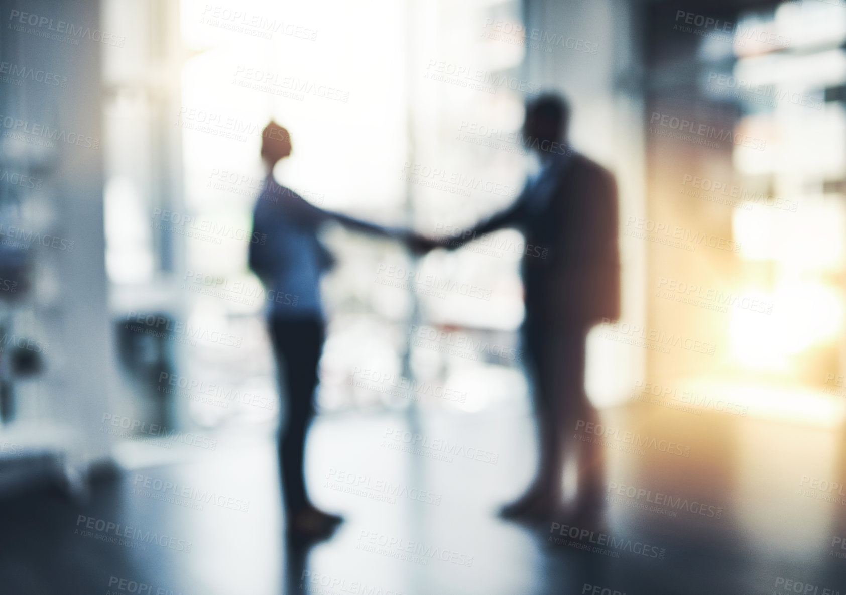 Buy stock photo Defocused shot of two businesspeople shaking hands in an office