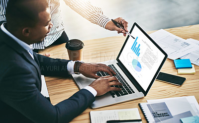 Buy stock photo Shot of two businesspeople analyzing graphs on a laptop in an office