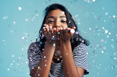 Buy stock photo Cropped shot of a beautiful young woman blowing confetti in the studio