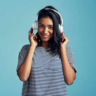 Buy stock photo Woman, portrait and headphones with music in studio with happiness and web audio. Blue background, Indian female person and young model listening, hearing and streaming a song with smile and online