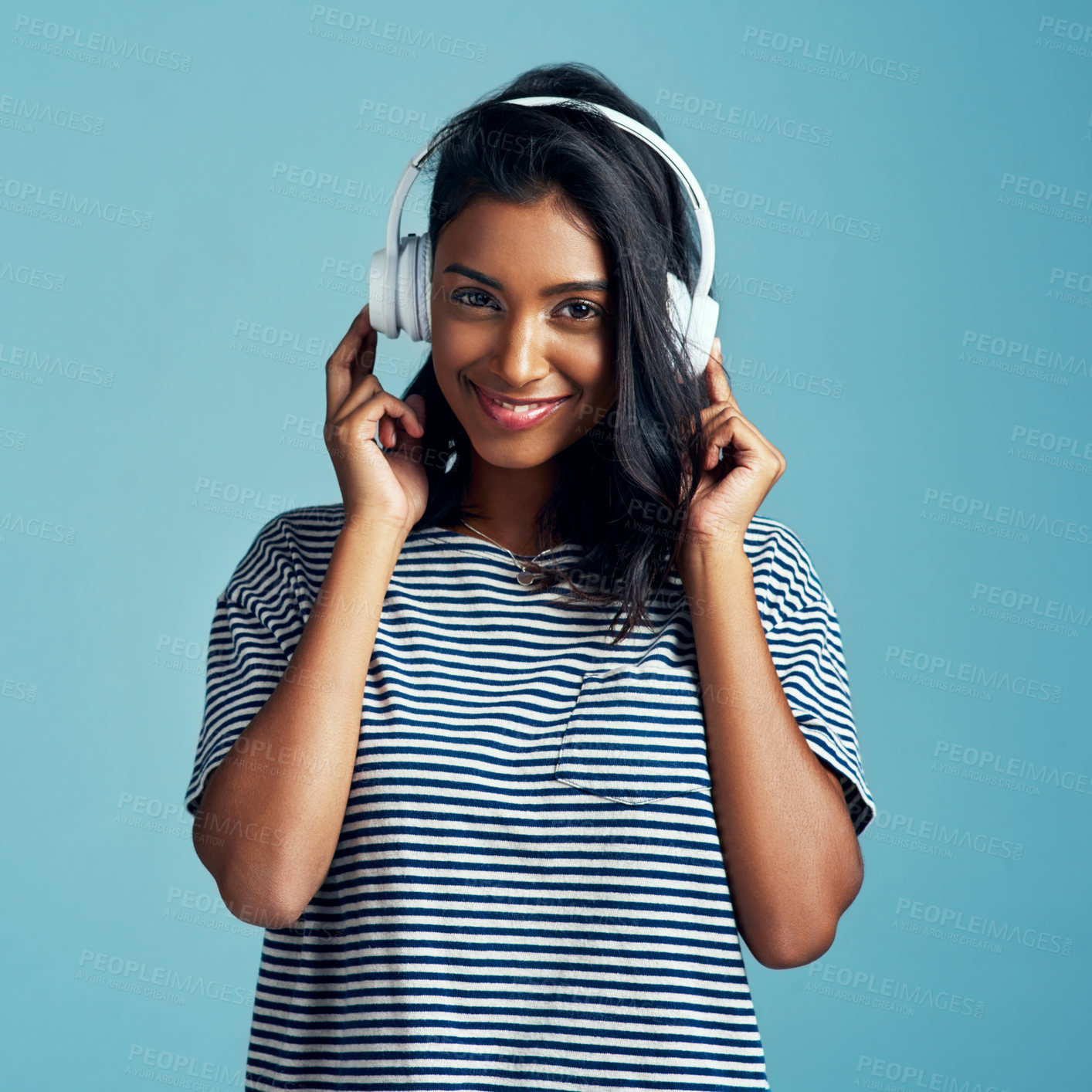 Buy stock photo Woman, portrait and headphones with music in studio with happiness and web audio. Blue background, Indian female person and young model listening, hearing and streaming a song with smile and online