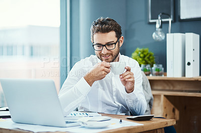 Buy stock photo Shot of a young businessman drinking a cup of tea while working in an office
