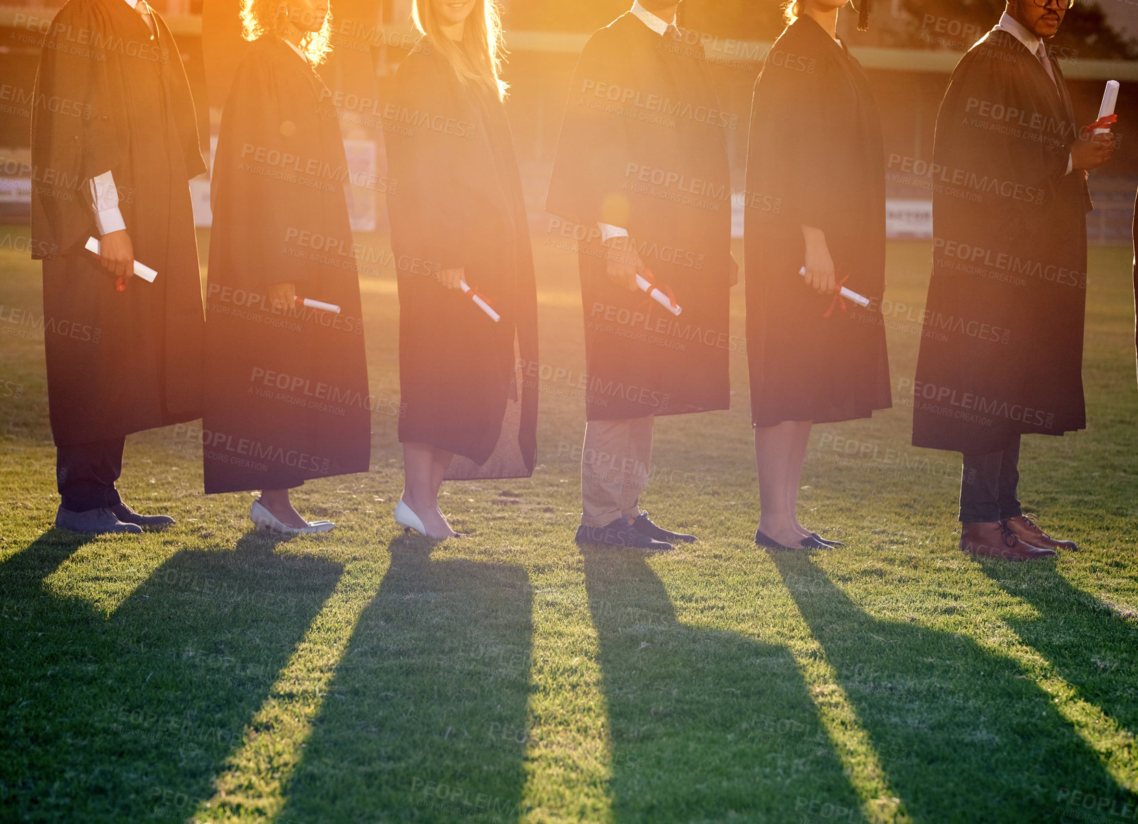 Buy stock photo Shot of a group of university students standing in line on graduation day