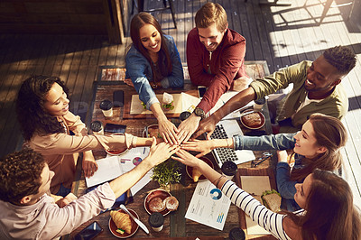 Buy stock photo High angle shot of a group of creative workers high-fiving while out on a business lunch