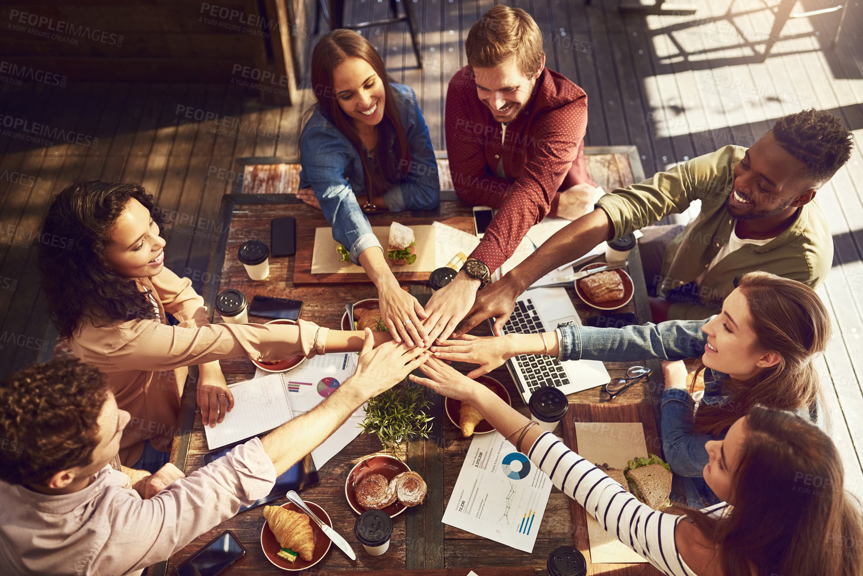 Buy stock photo High angle shot of a group of creative workers high-fiving while out on a business lunch