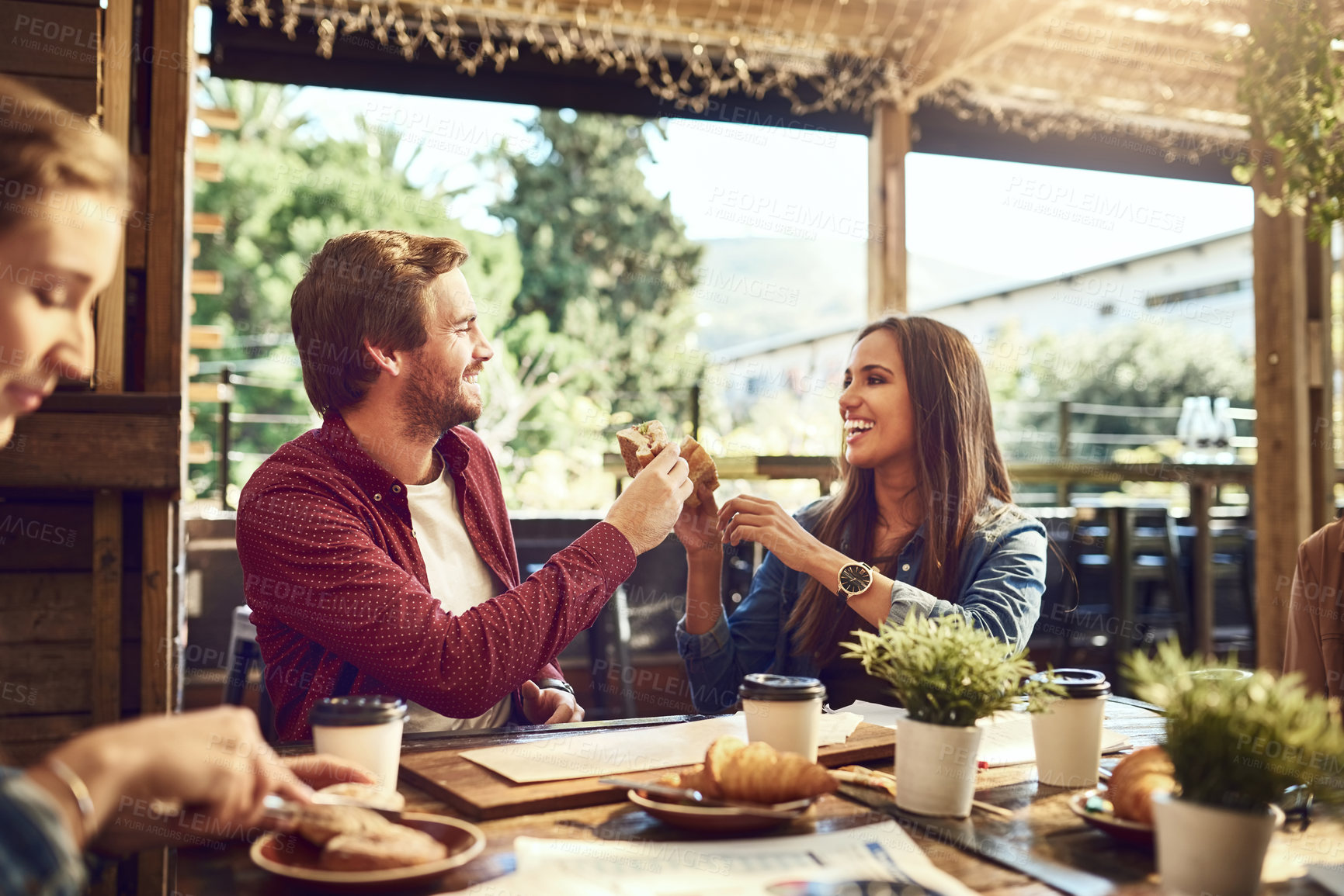 Buy stock photo Cropped shot of an affectionate young couple toasting with sandwiches while enjoying themselves at lunch