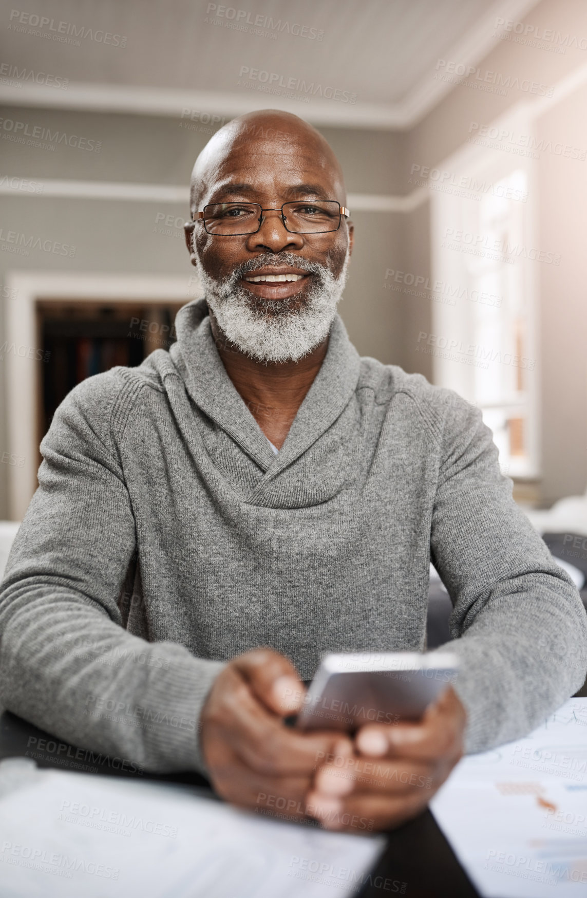 Buy stock photo Shot of a senior man using a mobile while working on his finances at home