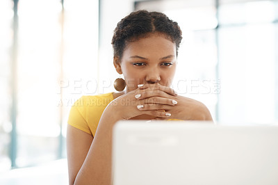 Buy stock photo Shot of a young businesswoman using a laptop at her desk in a modern office