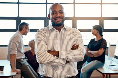 Buy stock photo Portrait of a confident young businessman standing in a modern office with his colleagues in the background