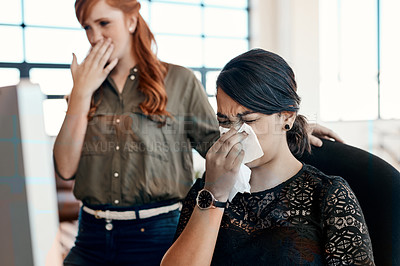Buy stock photo Shot of a young businesswoman blowing her nose at work with her colleague standing next to her