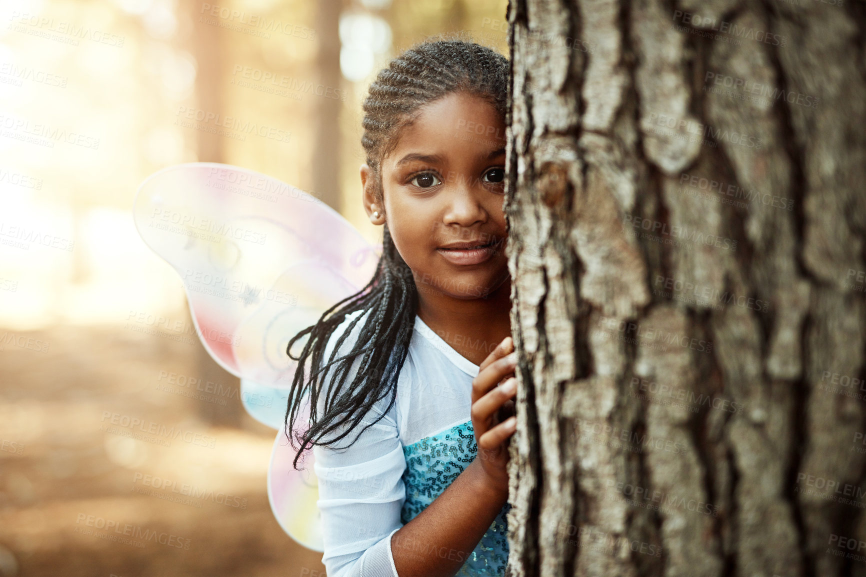 Buy stock photo Nature, forest and child in fairy costume for play, hide and portrait. Trees, relax and kid behind woods with wings, magical cosplay and outdoor childhood fun for picnic and travel adventure outdoors