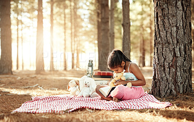 Buy stock photo Shot of a little girl reading a book with her toys in the woods