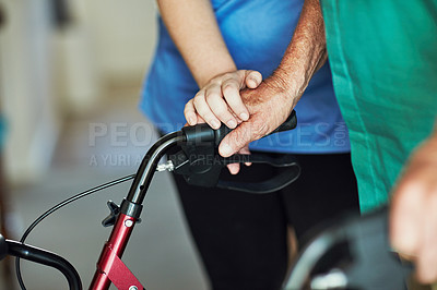 Buy stock photo Cropped shot of an unrecognizable female nurse assisting her senior patient who's using a walker for support