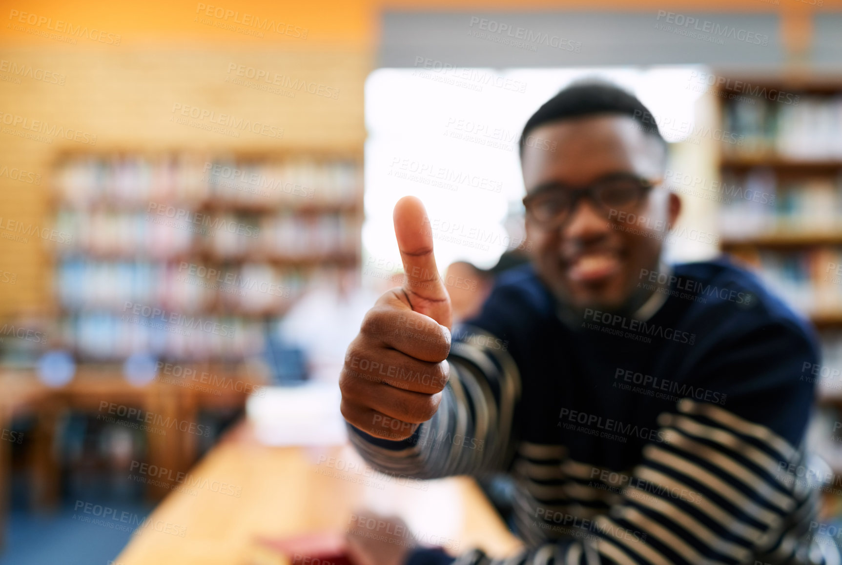 Buy stock photo Hands, thumbs up and student in library, man and sign for choice, review and happy for learning at campus. Person, smile and excited to study with icon, emoji or agreement for scholarship at college