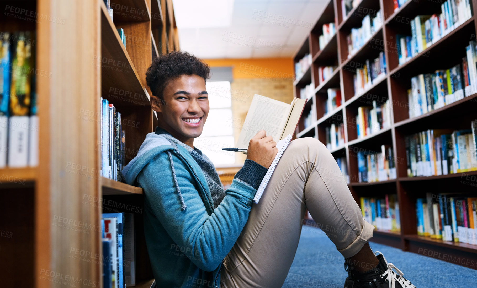 Buy stock photo Student, man and portrait with studying in library for scholarship, writing and reading a book for exam information. Education, person or happy with notebook for research notes and knowledge on floor
