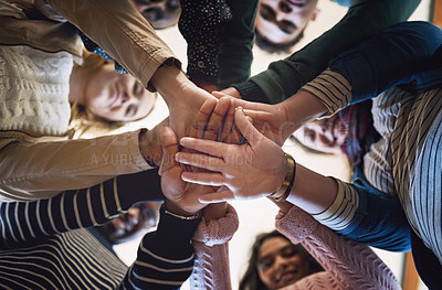Buy stock photo Low angle portrait of a group of young friends standing with their hands in a huddle