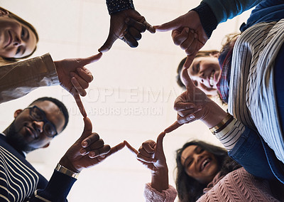 Buy stock photo Low angle portrait of a group of young friends standing in a huddle