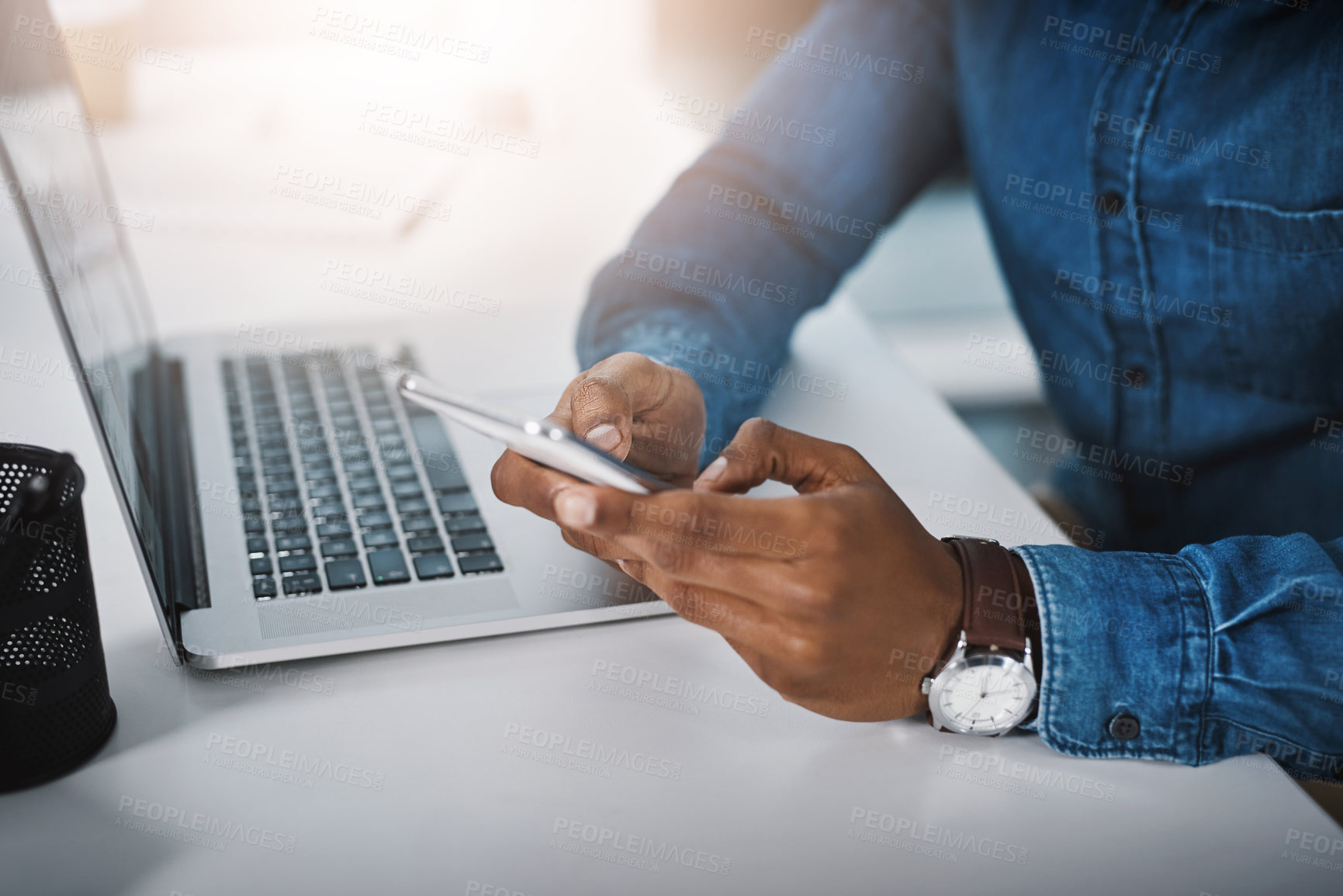 Buy stock photo Closeup shot of an unrecognizable businessman using a cellphone and laptop in an office