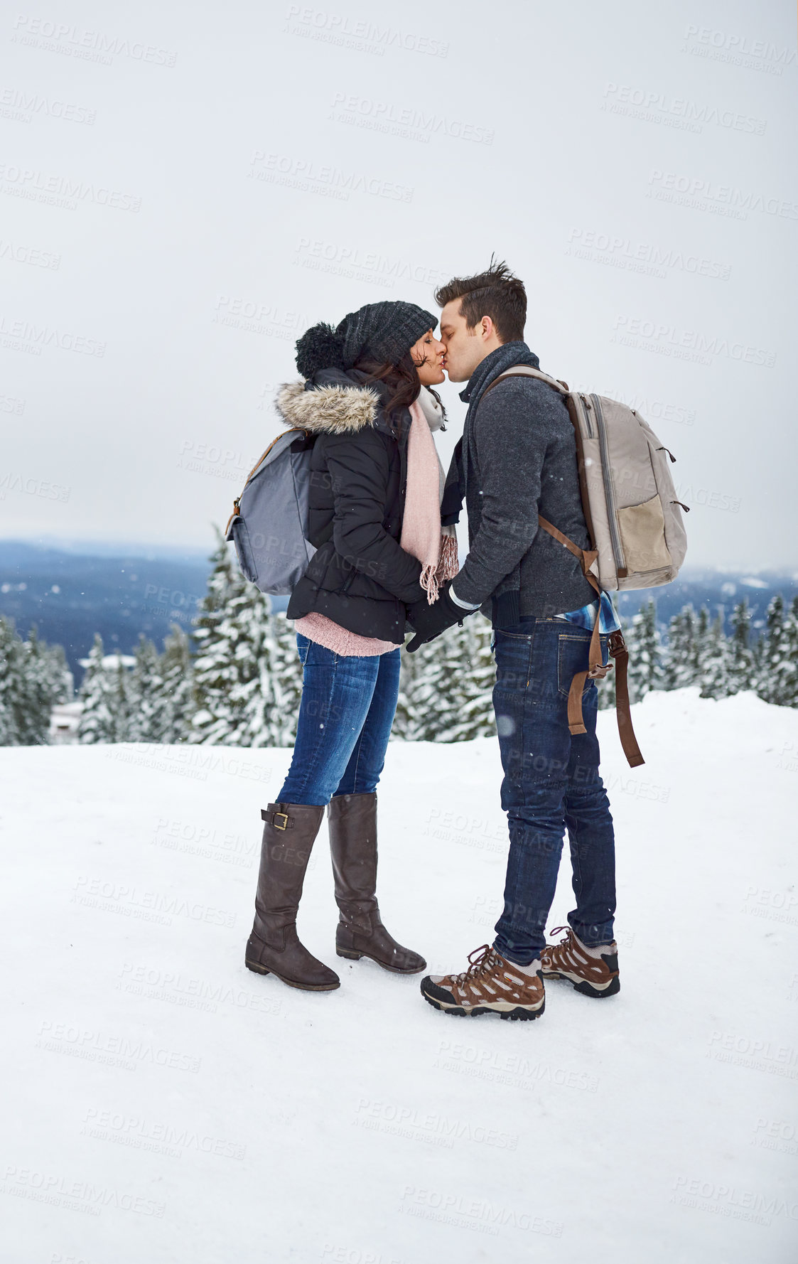 Buy stock photo Shot of a couple kissing while spending the day in the snow