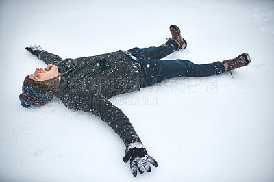 Buy stock photo Shot of a young man lying in the snow making a snow angel