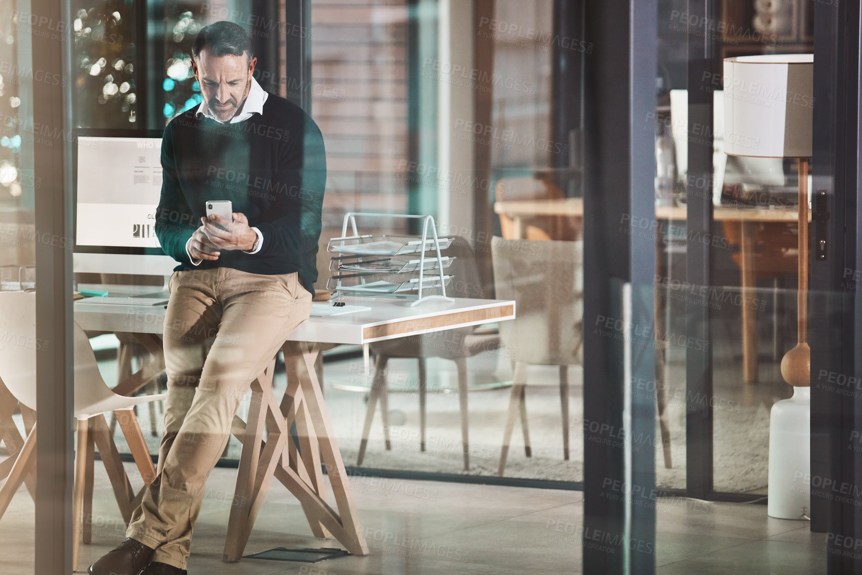 Buy stock photo Shot of a mature businessman using a mobile phone in a modern office