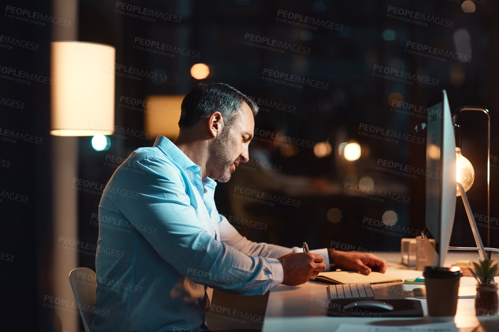 Buy stock photo Shot of a mature businessman using a computer during a late night at work