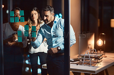 Buy stock photo Shot of a group of businesspeople having a brainstorming session at night in a modern office