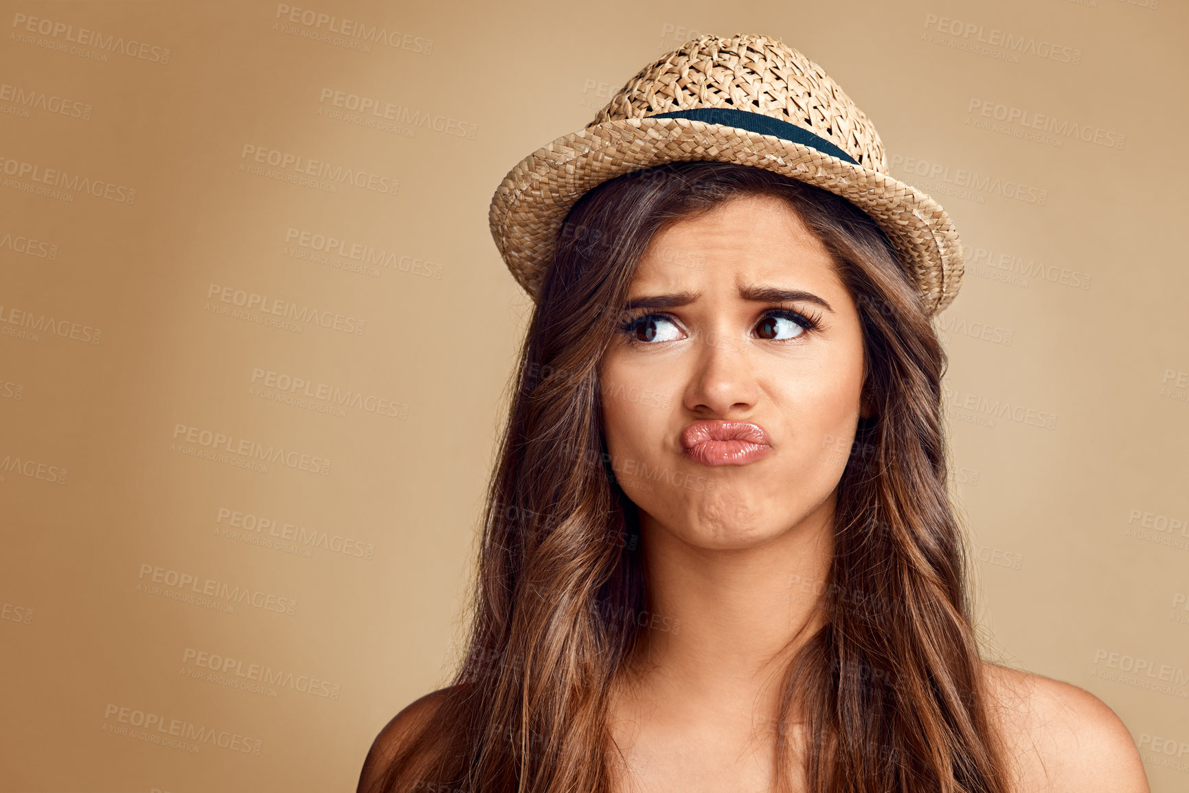 Buy stock photo Studio shot of a beautiful young woman looking thoughtful against a brown background