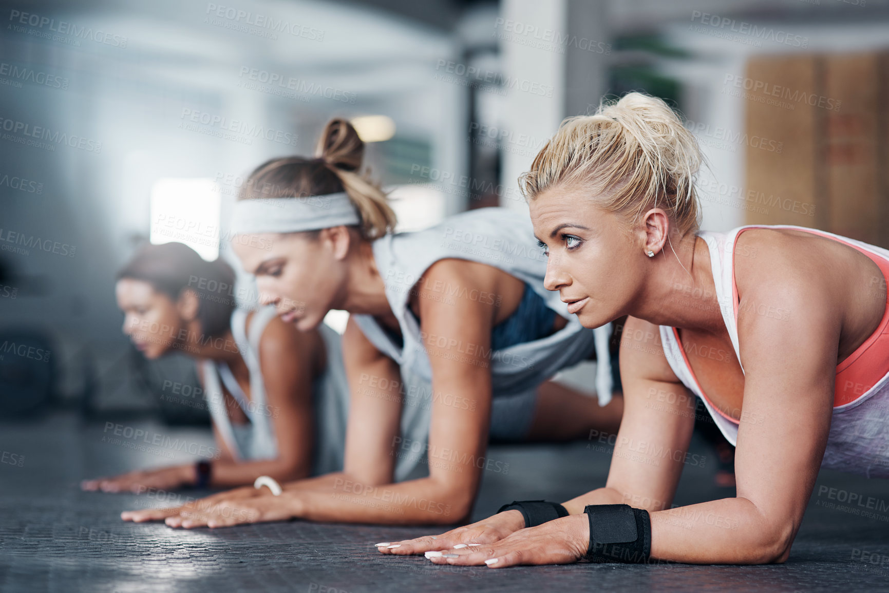 Buy stock photo Cropped shot of three women doing pushups at the gym