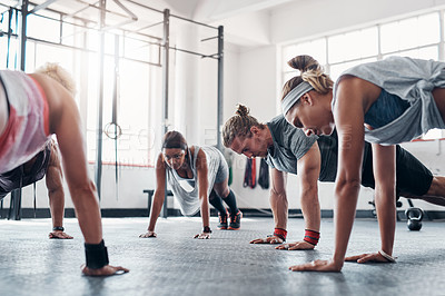 Buy stock photo Shot of an accountability group doing pushups at the gym
