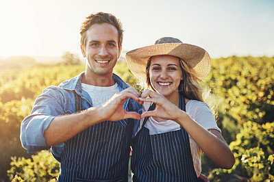Buy stock photo Cropped portrait of a young couple holding their hands together in a heart shape with their crops in the background