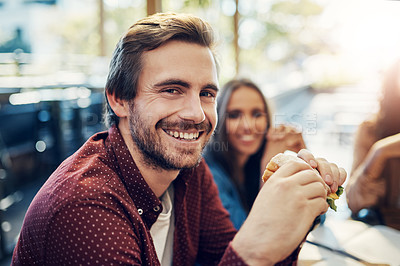 Buy stock photo Cropped portrait of a handsome young businessman enjoying his sandwich while having a breakfast meeting outside