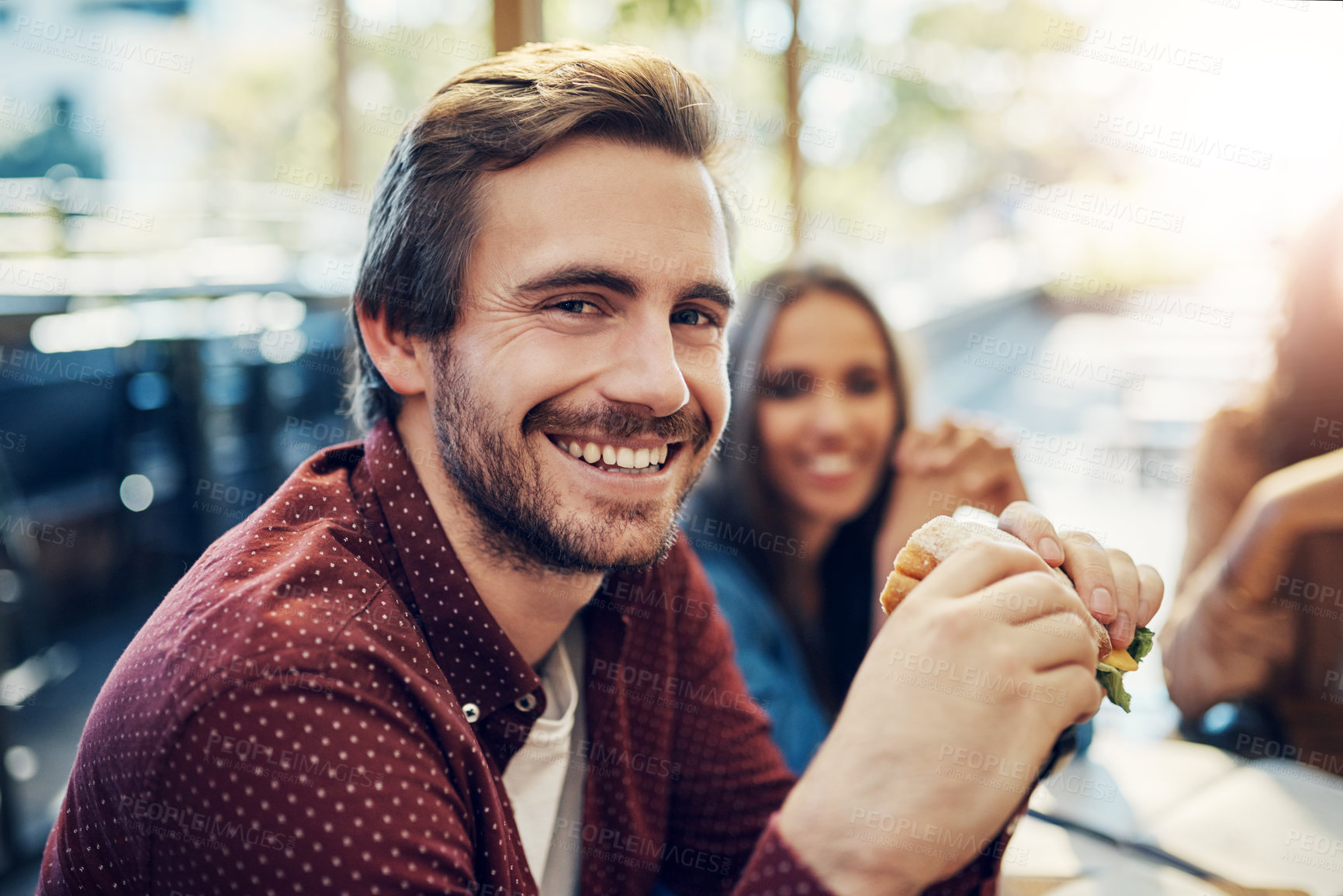 Buy stock photo Cropped portrait of a handsome young businessman enjoying his sandwich while having a breakfast meeting outside