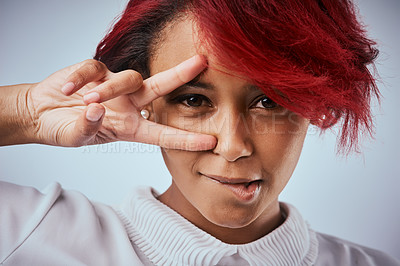 Buy stock photo Studio shot of a beautiful young woman showing the peace gesture over her eye