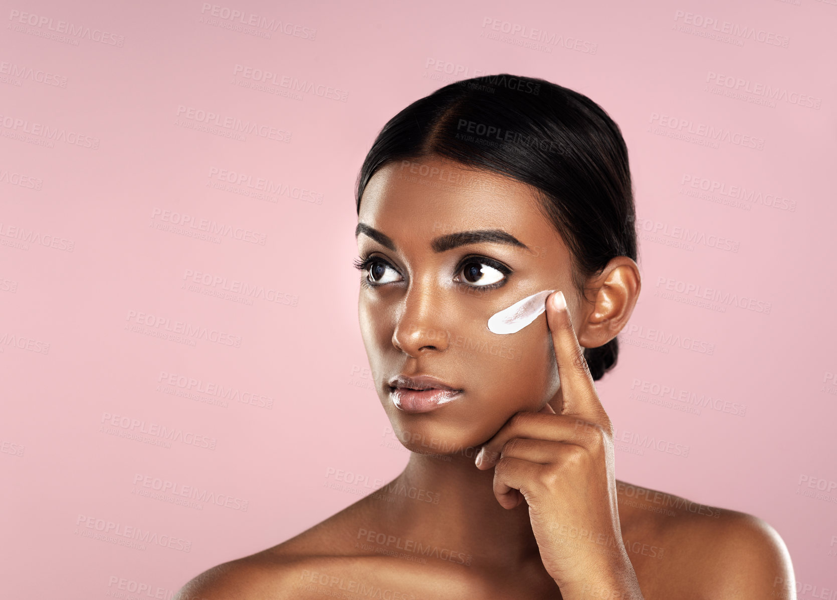 Buy stock photo Thinking, skincare and face of woman with cream in studio isolated on a pink background mockup. Dermatology, creme cosmetics and serious Indian female model apply moisturizer lotion for skin health.