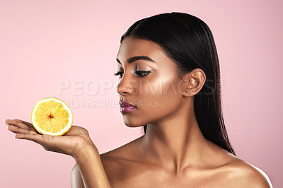 Buy stock photo Face, skincare and woman looking at an orange in studio isolated on a pink background. Fruit, natural cosmetics and Indian female model holding food for healthy diet, nutrition or vitamin c to detox.