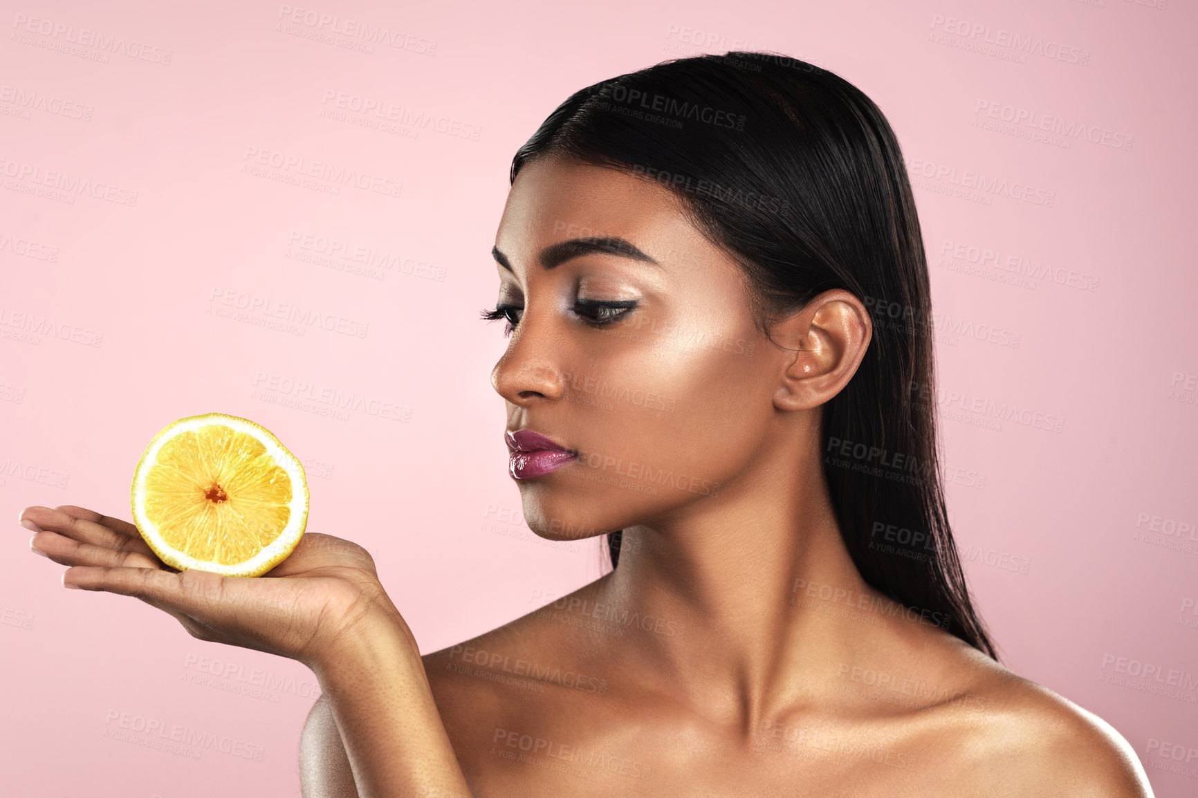 Buy stock photo Face, skincare and woman looking at an orange in studio isolated on a pink background. Fruit, natural cosmetics and Indian female model holding food for healthy diet, nutrition or vitamin c to detox.