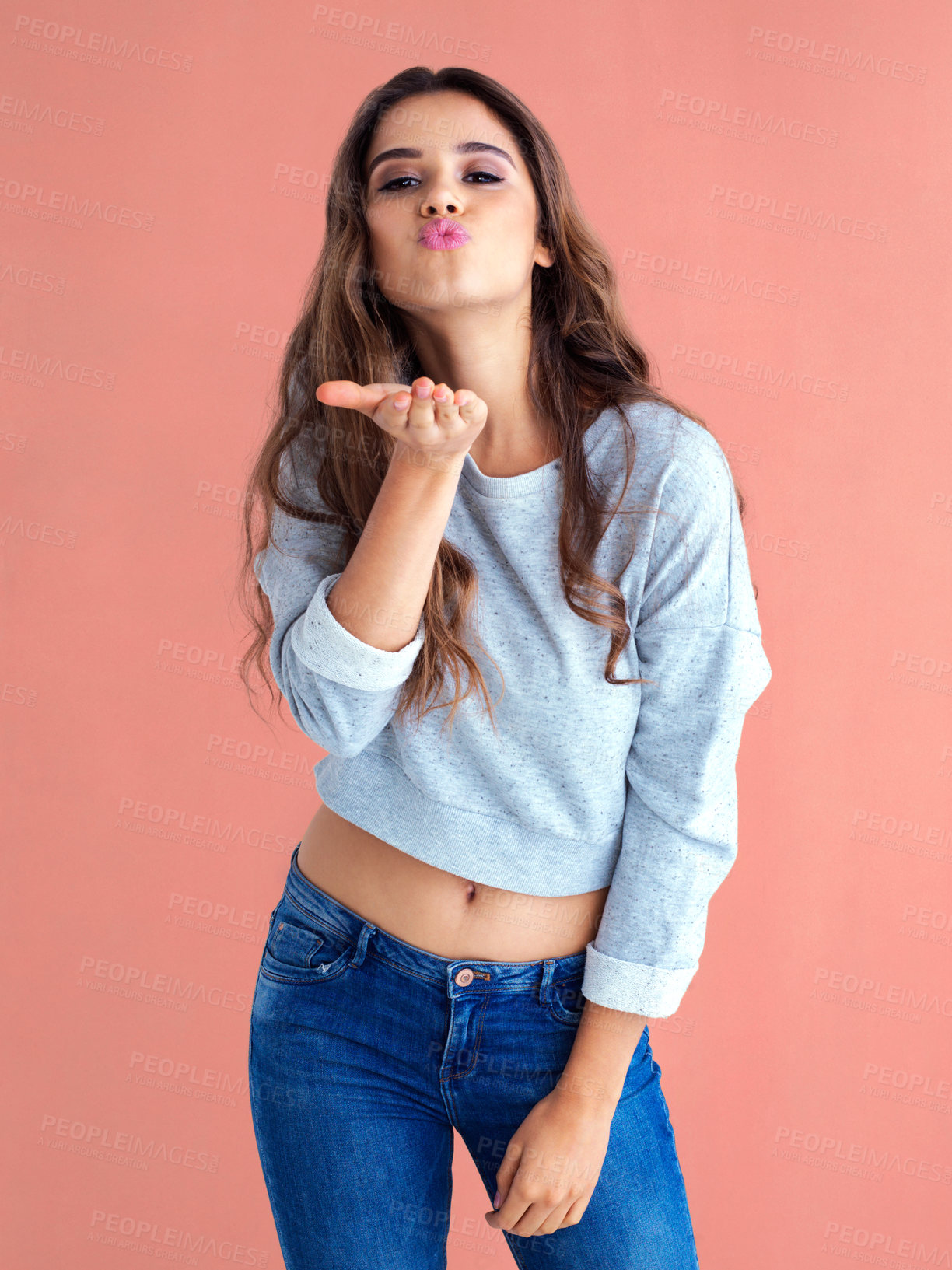 Buy stock photo Woman, blowing kiss and hand in studio portrait with pouting, lips or fashion by blue background. Girl, person and model with sign, clothes or streetwear for icon, symbol or emoji for love with mouth