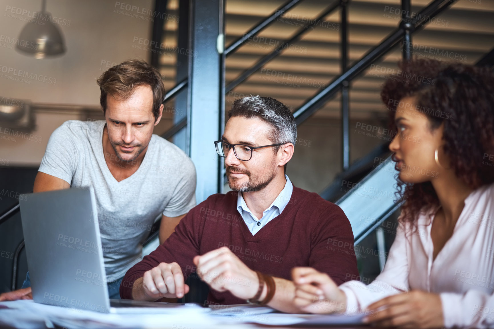 Buy stock photo Cropped shot of three designers discussing something on a laptop at work