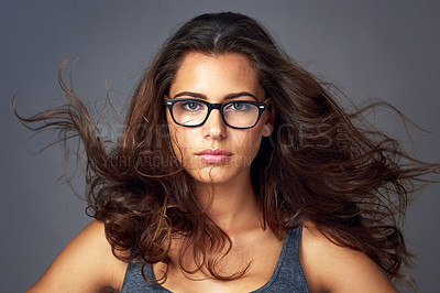 Buy stock photo Studio portrait of an attractive young woman wearing glasses against a grey background